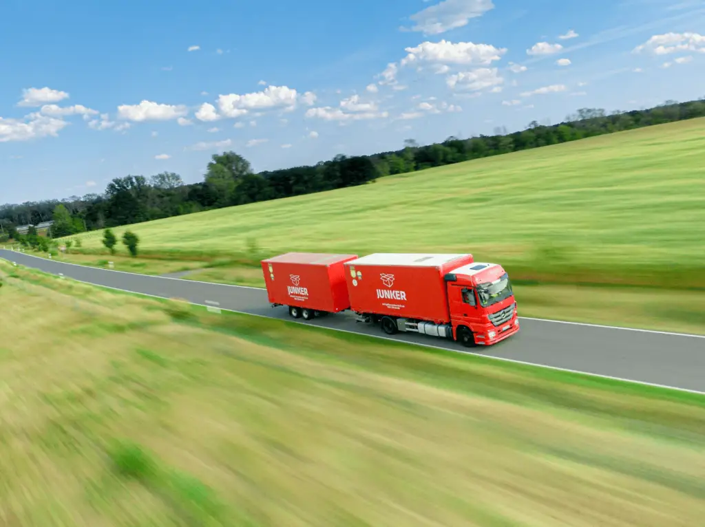 Junker Umzugs-LKW fährt auf einer Landstraße durch grüne Landschaft