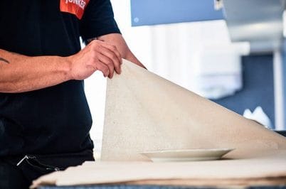 Junker-Mitarbeiter verpackt einen Teller mit Papier für den Umzug